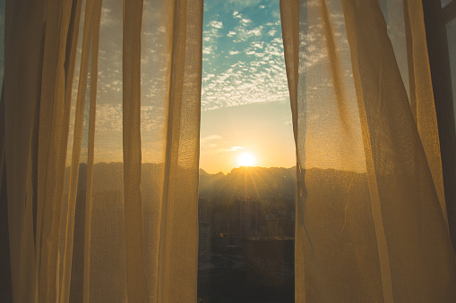 Sunlight filtering through soft curtains, creating a calm and reflective atmosphere.